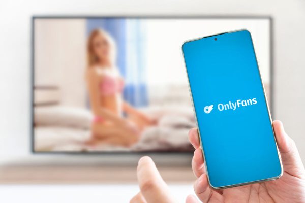 Barnaul. Russia March 28, 2023: OnlyFans logo on mobile phone in the hands of sexy women. OnlyFans is an internet paid content subscription service.