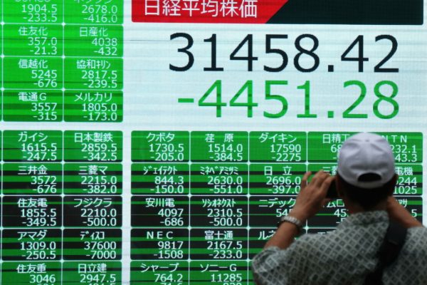 epa11526799 A pedestrian takes a photo of a display showing the closing information of the Nikkei Stock Average marking the biggest loss in history in Tokyo, Japan, 05 August 2024. The Tokyo stock benchmark was down 4,451.28 points, or 12.40 per cent, the biggest loss in history to close at 31,458.42.  EPA/KIMIMASA MAYAMA